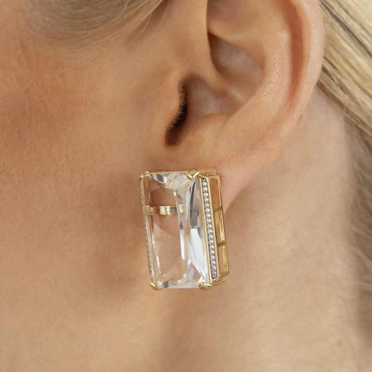 Modelo de perfil usando brinco maxi retangular de cristal transparente e zircônias dourado da Ahal Acessórios.