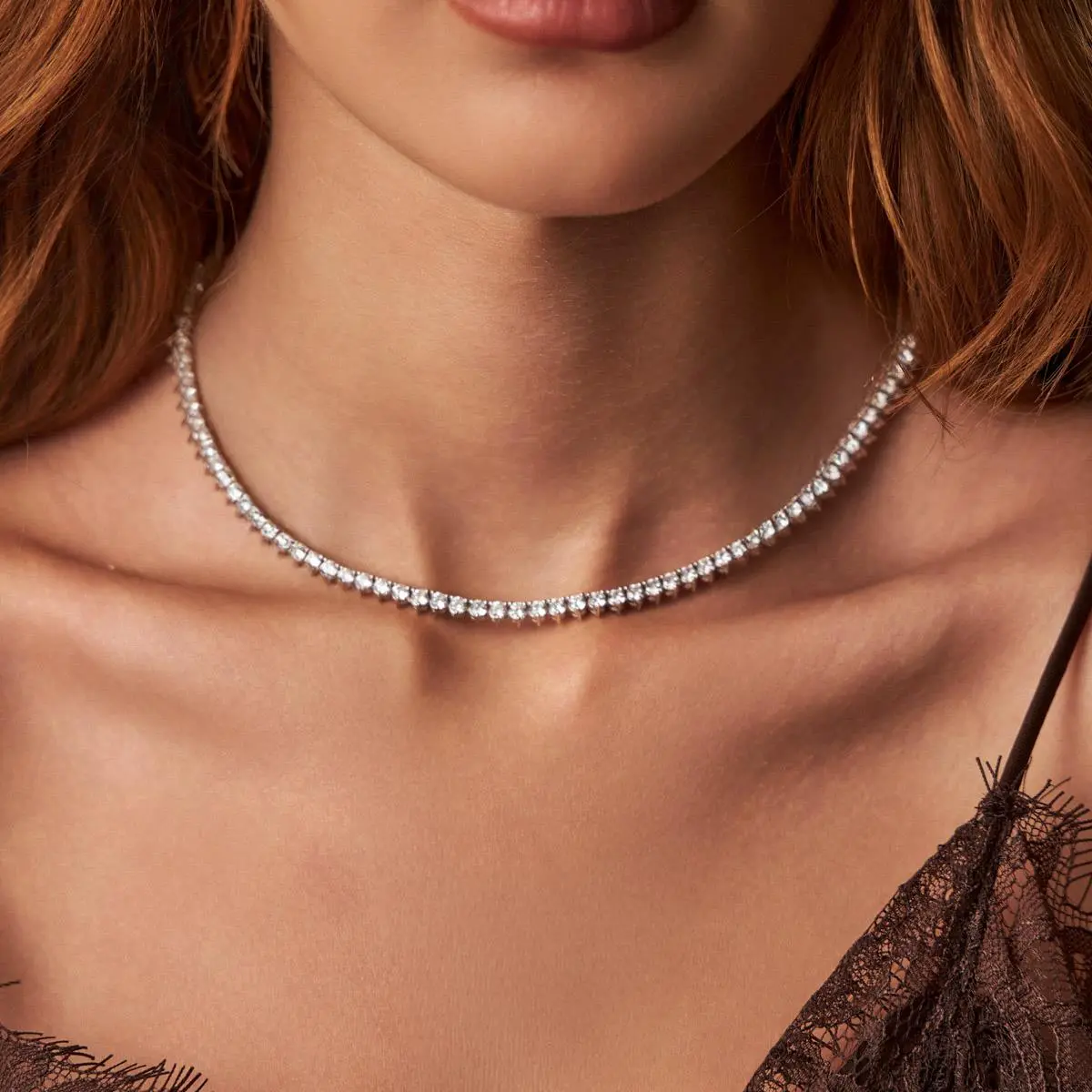 Modelo usando o colar riviera de cristais redondos incolores e banho de ródio branco ajustado perfeitamente ao pescoço, demonstrando o caimento e a proporção real da peça.
